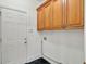 The laundry room features upper cabinets for storage and black tile flooring at 240 Flowers Cove Ln, Lilburn, GA 30047