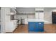 Contemporary kitchen featuring white cabinets, stainless steel appliances, a stylish blue island, and hardwood floors at 1430 N Harris Rdg, Atlanta, GA 30327