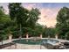 A luxurious pool area surrounded by a lush forest with outdoor decor, lounge chairs, and a jacuzzi at 1430 N Harris Rdg, Atlanta, GA 30327
