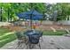 A fully fenced backyard with a brick retaining wall, stone patio, and seating shaded by an umbrella at 2633 Hanriva Ct, Dacula, GA 30019