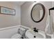 Powder room with a round mirror, pedestal sink, artwork, and wainscoting at 2633 Hanriva Ct, Dacula, GA 30019