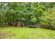 Large backyard featuring a playset and trampoline surrounded by trees at 305 Saddle Wood Dr, Canton, GA 30114