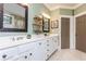 Green bathroom with double sinks, vanity, large framed mirror, and tile flooring at 730 Jackson Miller Cir, Powder Springs, GA 30127