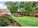 Private backyard with lush greenery, a covered area with wood and a stone fireplace at 4845 Willow St, Acworth, GA 30101
