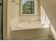Bathroom featuring a built in tub, exterior window, and tan colored tile at 2436 Green Hollow Ct, Conyers, GA 30012