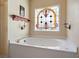 Bathroom featuring a soaking tub with stained glass window and gold fixtures at 3410 Kates Way, Duluth, GA 30097