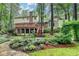 A serene backyard featuring a wooden deck, steps, and a stone pathway bordered by lush greenery and mature trees at 5507 Martina Way, Dunwoody, GA 30338