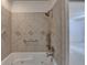 Bathtub with stone-look tile surround, elegant fixtures, and a hand-held shower head at 5507 Martina Way, Dunwoody, GA 30338