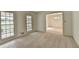 Sunlit living room with large windows and neutral carpeting leading into adjacent room at 5507 Martina Way, Dunwoody, GA 30338