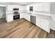 Well-lit kitchen featuring white cabinets, stainless steel appliances, and new wood flooring at 2734 Amber Springs Way, Buford, GA 30519