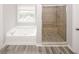 Bathroom features a soaking tub, a glass-door shower with custom tile, and gray wood-style tile flooring at 365 Hunt Creek Dr, Acworth, GA 30101