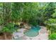 A private backyard with mature trees surrounds a stone-lined pool and spa, creating a serene retreat at 612 Champions Dr, Mcdonough, GA 30253