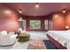 An interior view of a modern bedroom with marsala-painted walls, white seating, and tree views at 612 Champions Dr, Mcdonough, GA 30253