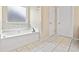 Bathroom featuring a soaking tub with marble backsplash and neutral tile flooring at 1212 Ashton Park Dr, Lawrenceville, GA 30045
