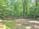A fenced-in playground with swings, slides, and a seesaw surrounded by a lush forest at 1625 Clark Lake Nw Dr, Acworth, GA 30102