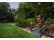 Landscaped backyard featuring a small bridge over a dry creek bed with stone borders and green lawn at 390 Hembree Rd, Roswell, GA 30075