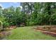 Spacious backyard featuring a large grassy area, wooden deck, garden beds, and playhouse at 125 Winter Valley Ct, Fayetteville, GA 30215
