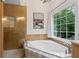 Bright bathroom features a soaking tub with patterned tile surround and a glass-enclosed shower at 125 Winter Valley Ct, Fayetteville, GA 30215