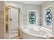 Bathroom featuring glass enclosed shower, corner tub, decorative stained glass windows, and tile accents at 2610 Ginger Dr, Buford, GA 30519