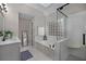 This full bathroom features a glass block window, a soaking tub, a walk-in shower, white tile, and gray accents throughout at 1143 Brookhaven North Cir, Brookhaven, GA 30319