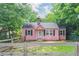 Charming pink cottage-style home with black shutters and a well-maintained front yard surrounded by mature trees at 207 Walthall Nw St, Marietta, GA 30064