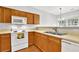 Cozy kitchen featuring wooden cabinets, white appliances, and laminate countertops at 4055 Hill Station Ct, Sugar Hill, GA 30518