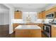 Bright kitchen with an island, stainless steel appliances, wood cabinets, and hardwood flooring at 6360 Waveland Dr, Cumming, GA 30040