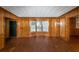 An empty living room featuring wood paneling, hard flooring, and natural light through a window at 2017 S Deshon Rd, Lithonia, GA 30058