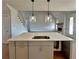 The kitchen island features a sink, sleek cabinetry, and stylish pendant lighting at 301 Eminence Peak, Rydal, GA 30171