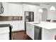 Close-up of a bright white kitchen featuring stainless steel appliances and a large island with modern pendant lighting at 4945 Racquet Ct, Duluth, GA 30096