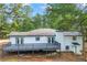 Back exterior featuring a spacious deck, white painted brick, and mature trees at 1377 Hill Sw Dr, Conyers, GA 30094