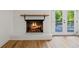 Cozy fireplace with brick surround and hearth with wooden mantel and French doors leading to an outdoor space at 1377 Hill Sw Dr, Conyers, GA 30094
