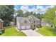 View of brick two-story home with mature trees, manicured lawn, and two-car garage at 445 Sweet Ivy Ln, Lawrenceville, GA 30043