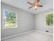 This bedroom has neutral walls and carpet, two windows, and a ceiling fan with light kit at 2578 Morgan Lake Ne Dr, Marietta, GA 30066