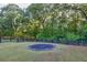 The back yard features lush greenery, dark wood fencing, and a trampoline at 401 Pirkle Ave, Buford, GA 30518