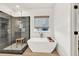Bright bathroom featuring large tub, a rainfall shower behind glass, and a window at 401 Pirkle Ave, Buford, GA 30518