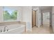 Bright bathroom featuring a modern tub, shower, and neutral tile with natural light from the window at 2040 Bloomfield Ct, Cumming, GA 30041