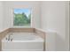 Bright bathroom featuring a modern tub with stylish tile surround and natural light from the window at 2040 Bloomfield Ct, Cumming, GA 30041