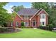 Charming two-story red brick home featuring manicured lawn, mature trees, and classic architectural details at 963 Bolingbrook Sw Dr, Marietta, GA 30064