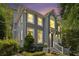 Beautiful gray painted brick home with white trim surrounded by mature trees and manicured landscaping at dusk at 29 Greenland Trce, Atlanta, GA 30342