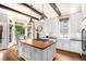 Open kitchen with a wood-topped island, white cabinets, and a view of the breakfast nook bathed in natural light at 29 Greenland Trce, Atlanta, GA 30342