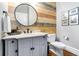 Stylish powder room with wood accent wall, round mirror, and modern fixtures at 29 Greenland Trce, Atlanta, GA 30342