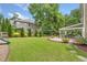 Large backyard with lush green grass, mature trees, and a covered patio area at 3260 Caney Creek Ln, Cumming, GA 30041