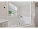 Bathroom featuring a soaking tub, a window with privacy blinds, and white fixtures at 3260 Caney Creek Ln, Cumming, GA 30041