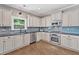 Bright kitchen features white cabinetry, stainless appliances, dark countertops, and hardwood floors at 3260 Caney Creek Ln, Cumming, GA 30041