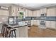 Bright kitchen features white cabinetry, stainless appliances, dark countertops, and hardwood floors at 3260 Caney Creek Ln, Cumming, GA 30041