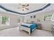 Spacious main bedroom featuring tray ceiling, ceiling fan, and plenty of natural light from the surrounding windows at 3260 Caney Creek Ln, Cumming, GA 30041