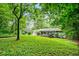 Expansive backyard with lush greenery, features a deck, a pool house, and mature trees at 3317 Embry Hills Dr, Atlanta, GA 30341
