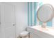 Cozy powder room features wainscotting stripes, toilet, vanity, and round mirror at 3758 Lake Haven Way, Atlanta, GA 30349