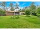 Lush backyard with green lawn, garden, and brick house, creating a peaceful and inviting outdoor space at 597 Rich Davis Rd, Hiram, GA 30141